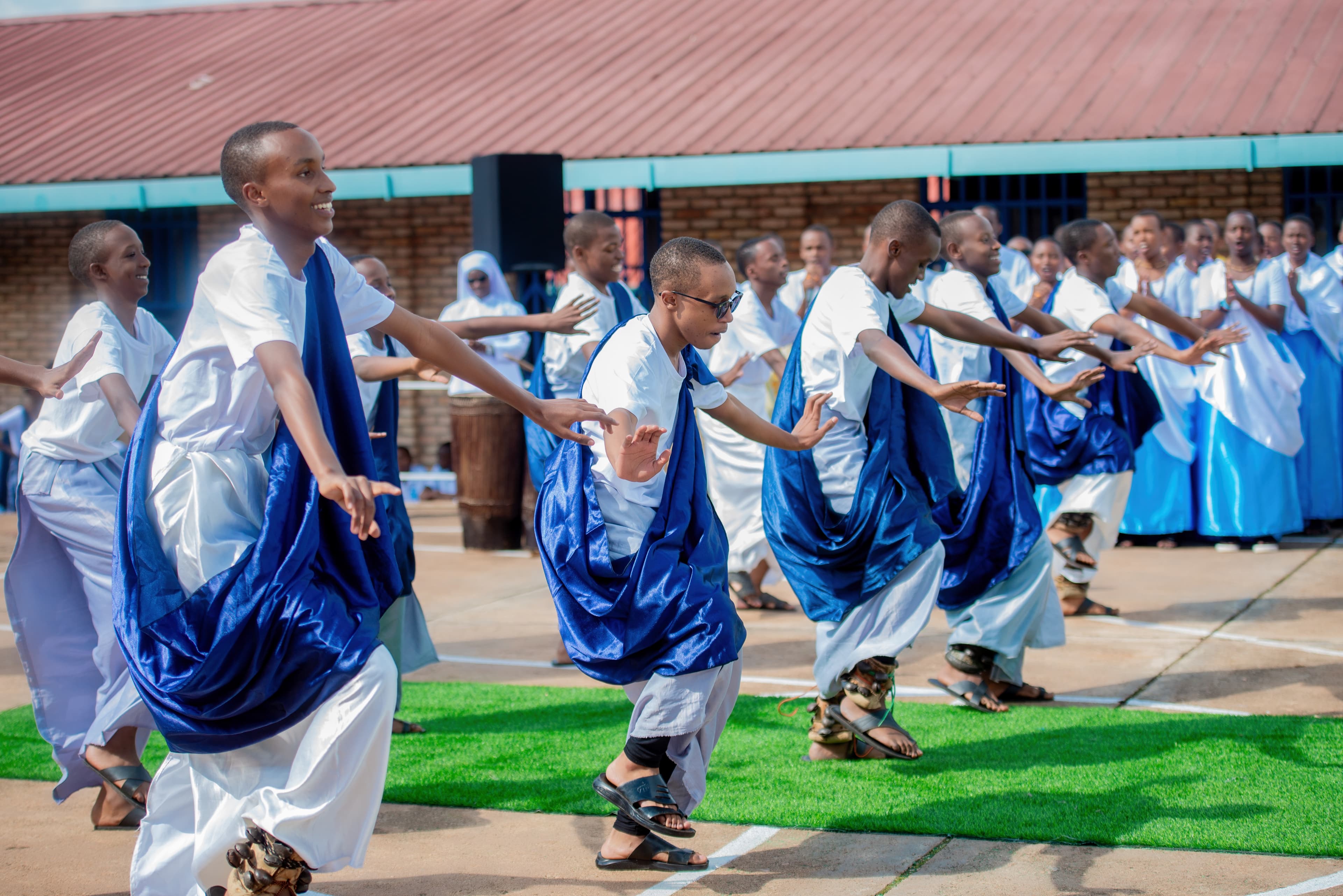 Students dancing in traditional attire or playing football on the school field.