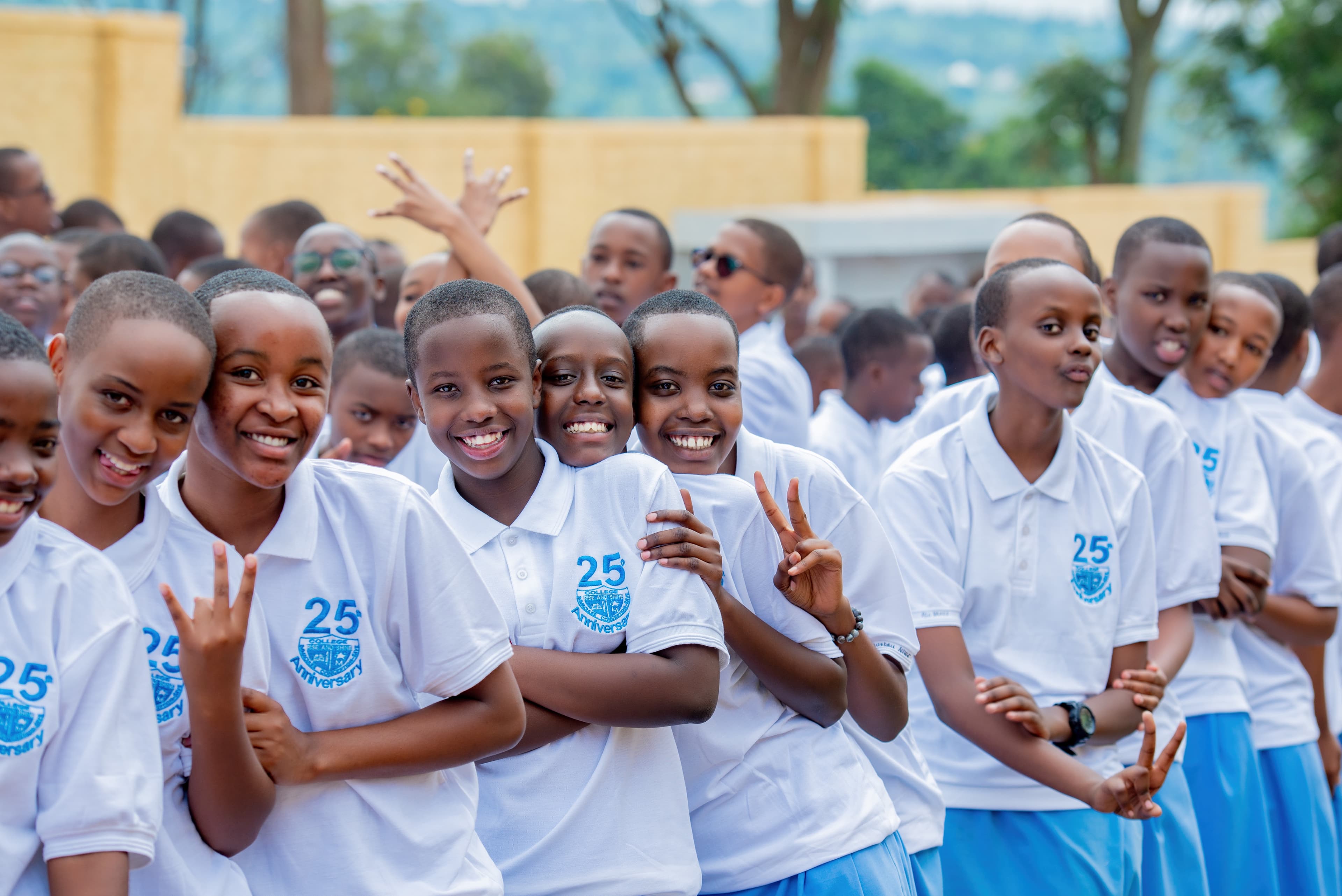 Students hugging or smiling in uniform, standing proudly in front of the school.